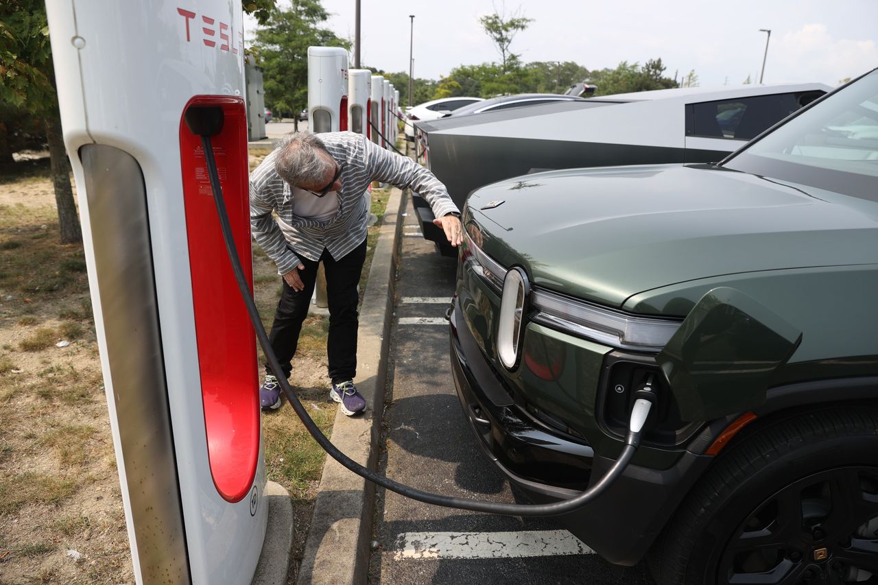 Boston Globe reporter Aaron Pressman charges a Rivian SUV at a Tesla Supercharger. (Photo by Jonathan Wiggs/The Boston Globe via Getty Images)