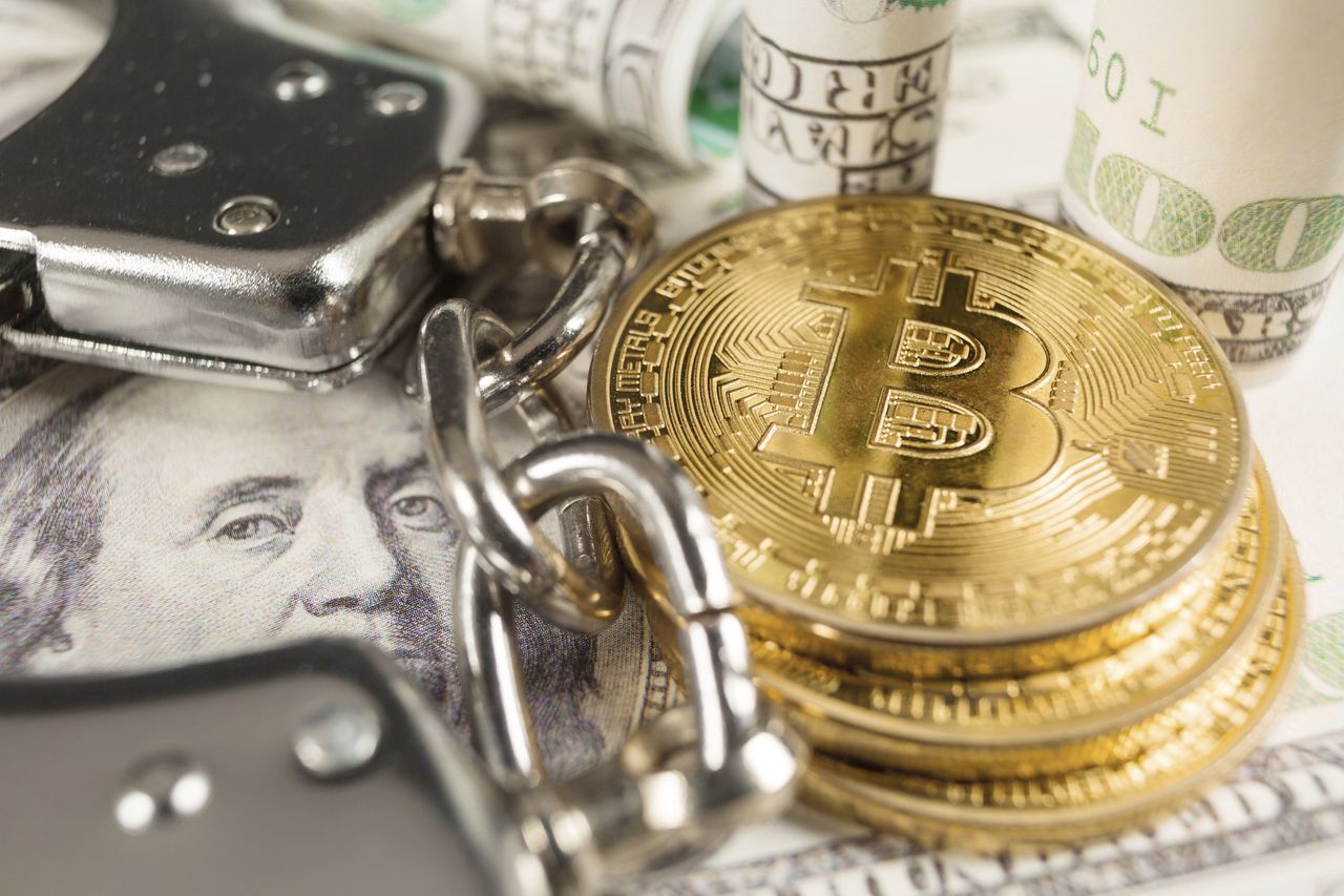  Golden Bitcoins Cryptocurrency with Handcuffs on Dollar bills. Digital crime, arrest or hacking concept - stock photo