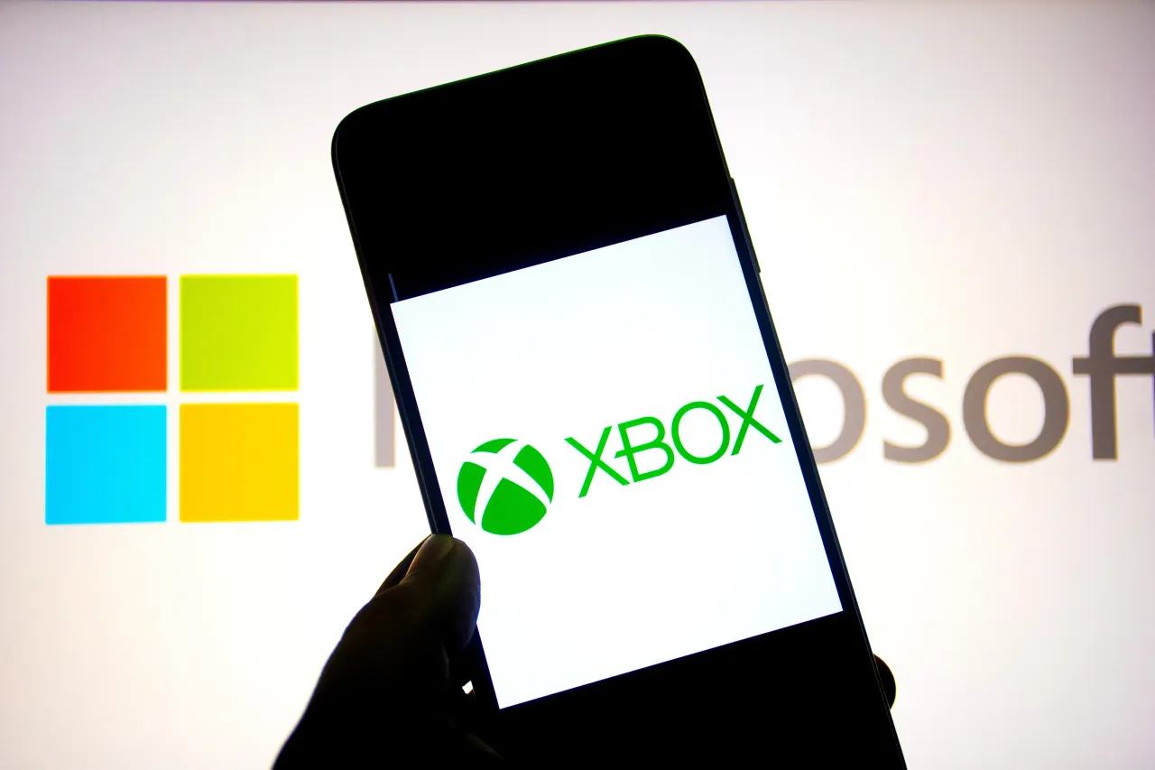 In this photo illustration, a Xbox logo seen displayed on a smartphone with a Microsoft Logo in the background. 