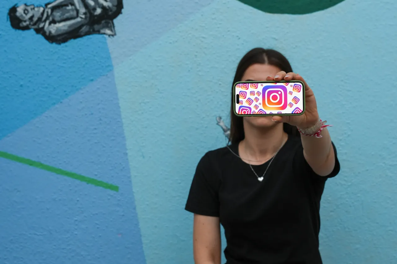 A woman holding a phone with its screen showing the Instagram logo. (Photo by Dilara Irem Sancar/Anadolu via Getty Images)