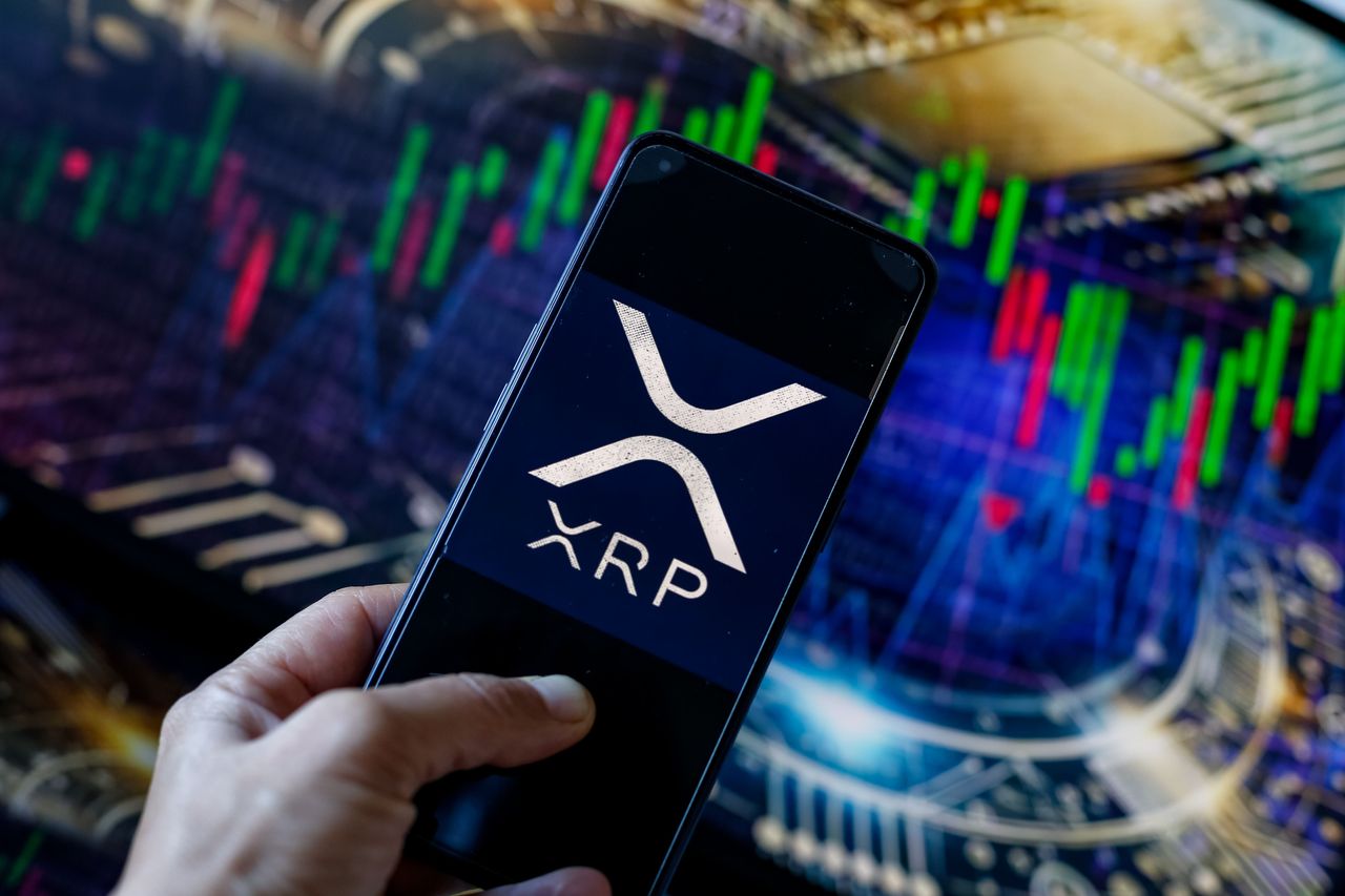 In this photo illustration, the XRP logo seen displayed on a smartphone with stock market graphs in the background. (Photo Illustration by Dominika Zarzycka/SOPA Images/LightRocket via Getty Images)