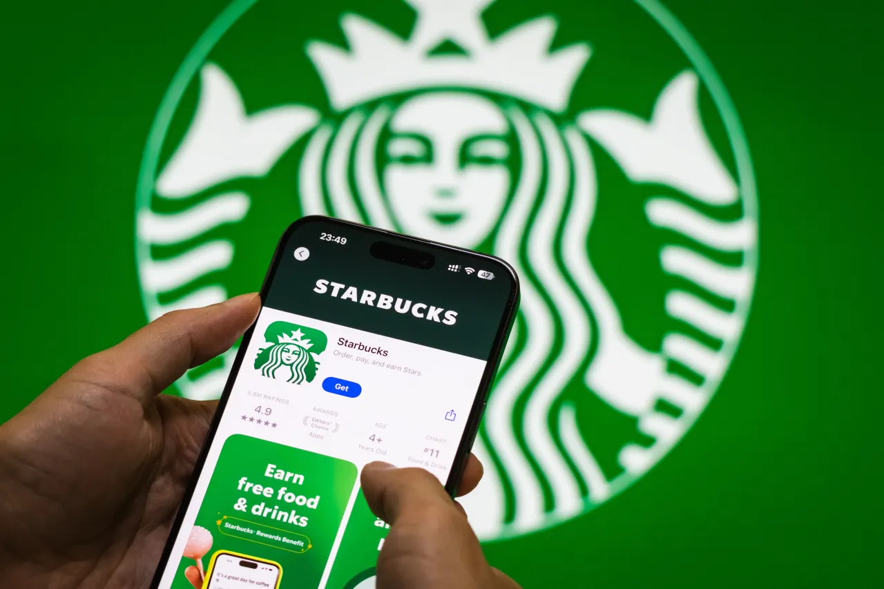 The Starbucks app page is displayed on a smartphone in front of the Starbucks corporate logoStarbucks has appointed Amazon tech leader Anand Varadarajan as its CTO. (Photo by Cheng Xin/Getty Images)