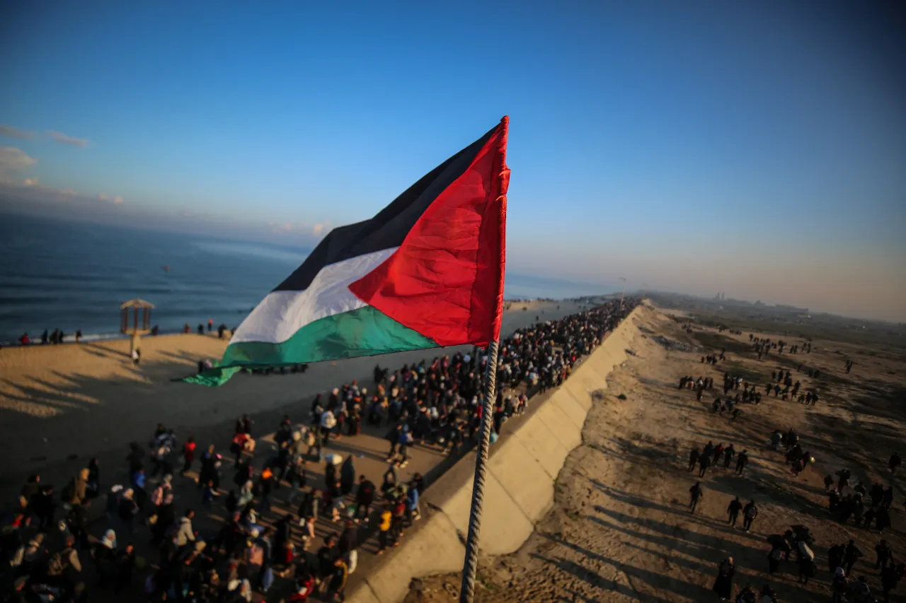 A waving Palestinian flag is seen as tens of thousands of Palestinians return to their houses through Al-Rashid Street. (Photo by Ali Jadallah/Anadolu via Getty Images)