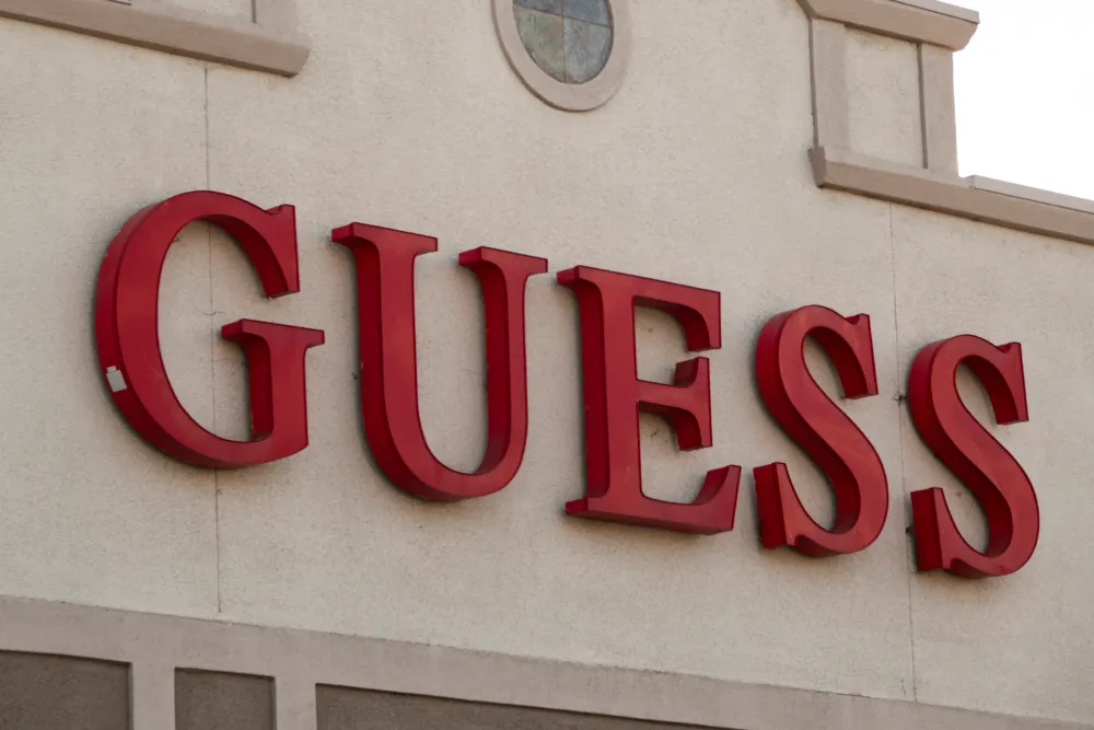 The Guess corporate logo is displayed on a sign at their store on January 31, 2025 in San Diego, California. (Photo by Kevin Carter/Getty Images)