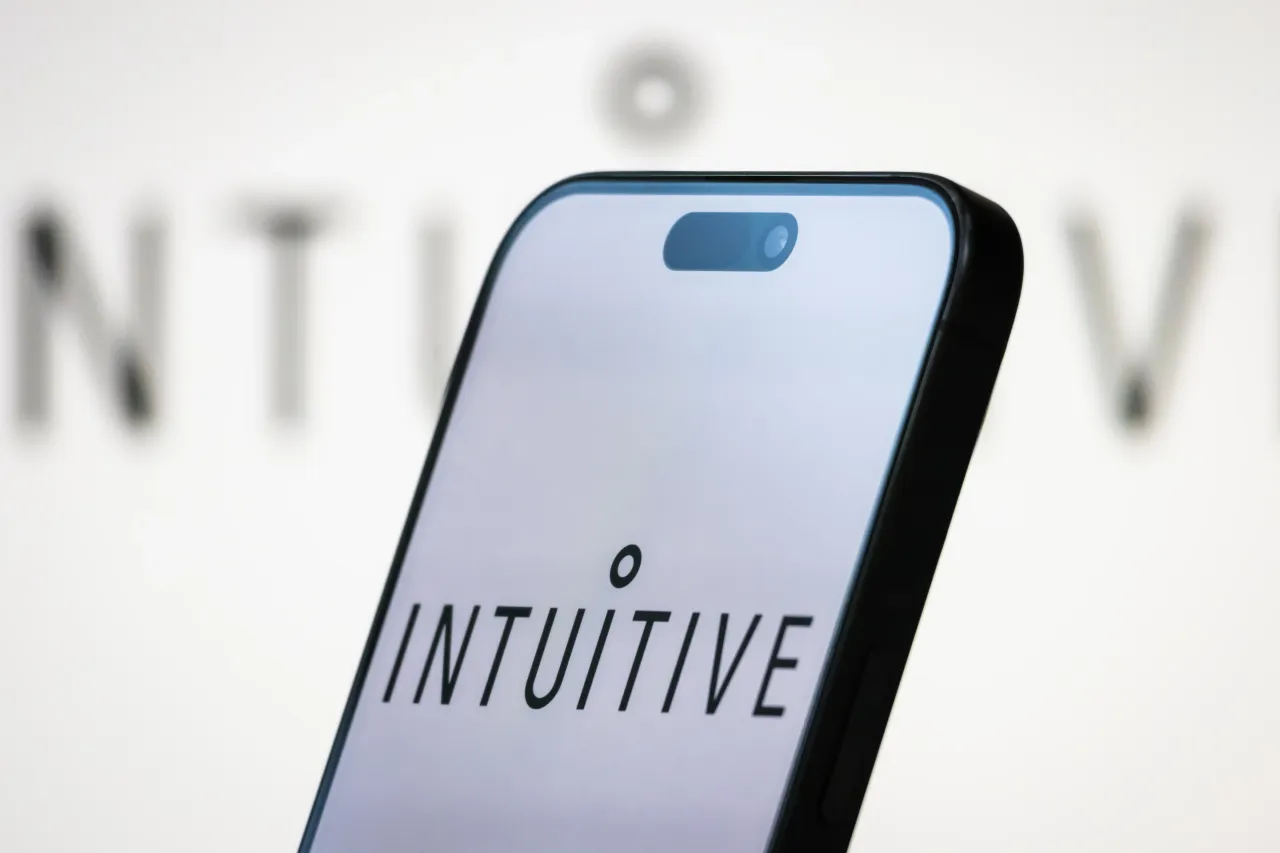 In this photo illustration, the logo of Intuitive Surgical, Inc. is displayed on a smartphone screen, with the company's branding in the background. (Photo by Cheng Xin/Getty Images)