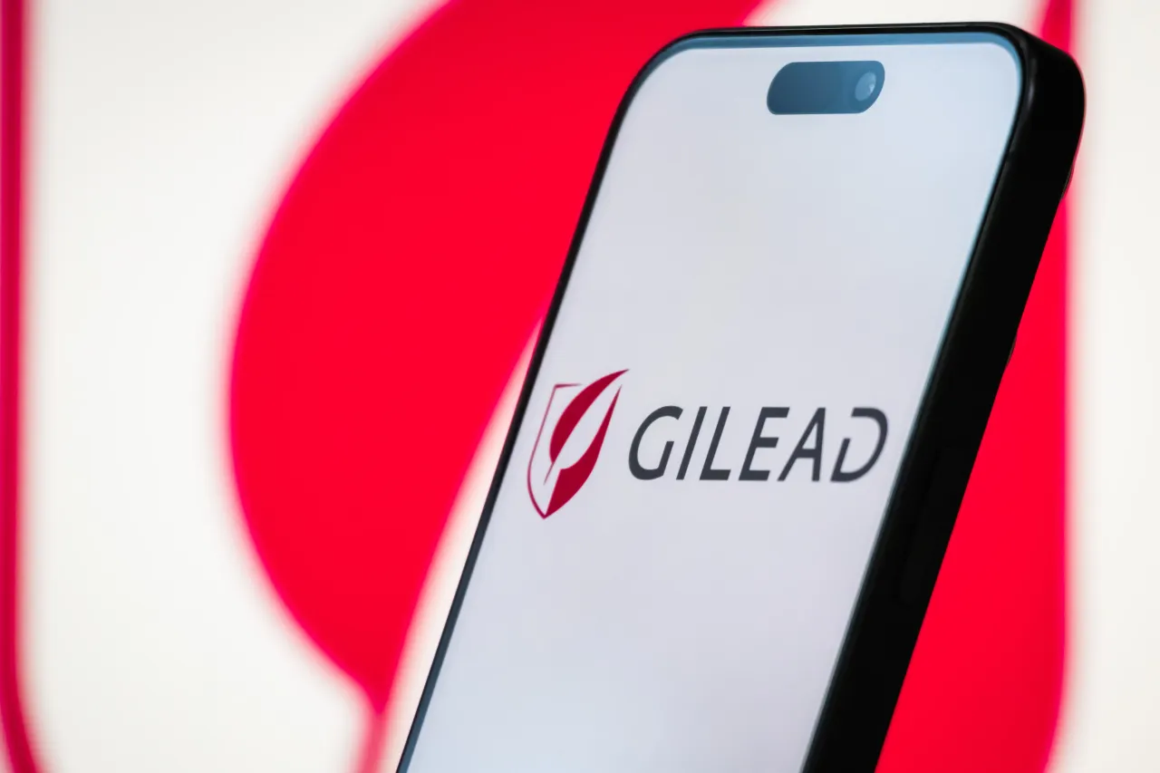 In this photo illustration, the Gilead Sciences logo is displayed on a smartphone screen, with the company's branding visible in the background, on April 20, 2025, in Chongqing, China. (Photo illustration by Cheng Xin/Getty Images)