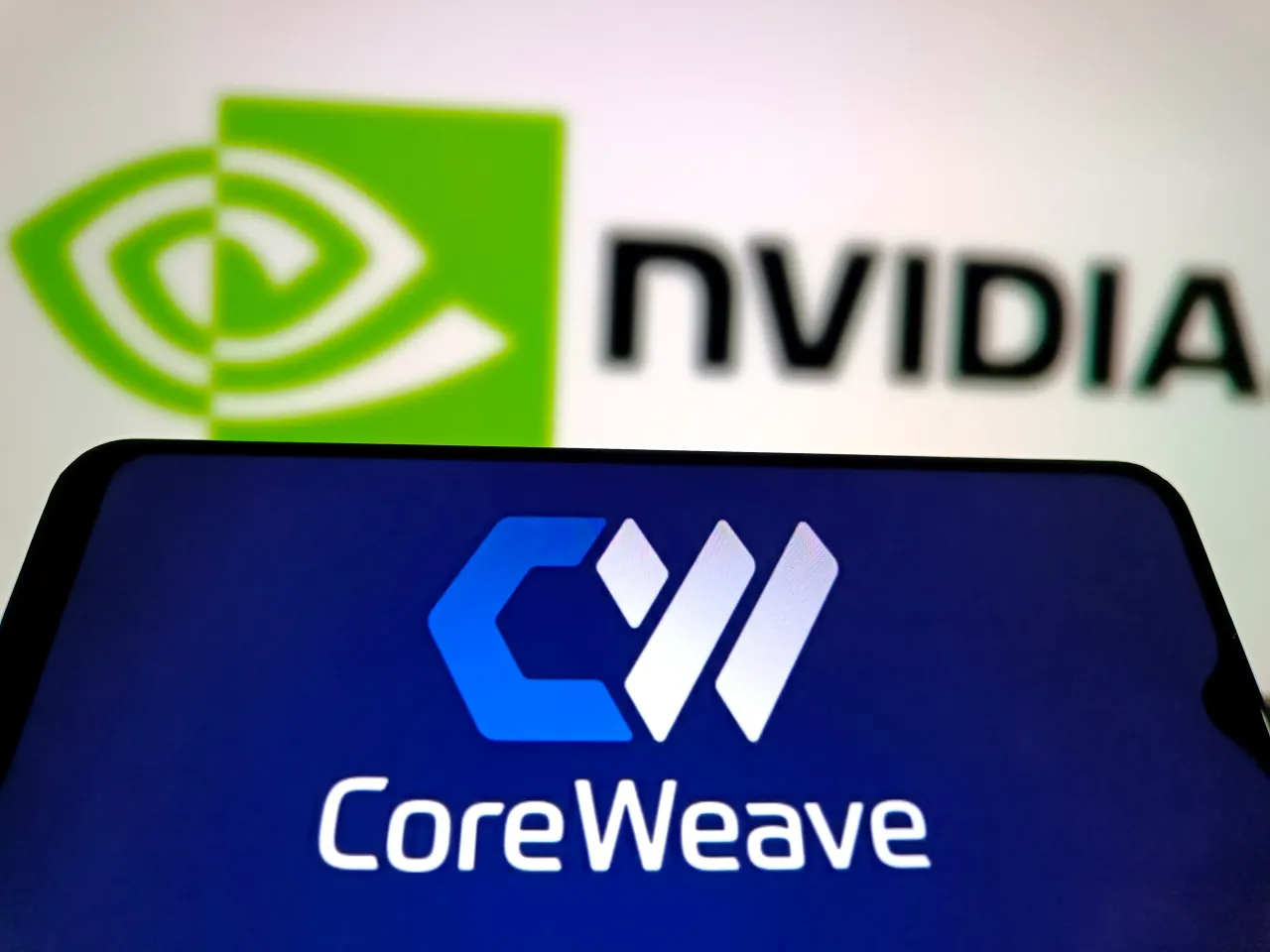 In this photo illustration, the logo of AI cloud-computing startup CoreWeave is displayed on a smartphone screen with Nvidia logo in the background on May 16, 2025 in Suqian, Jiangsu Province of China. (Photo by VCG/VCG via Getty Images)