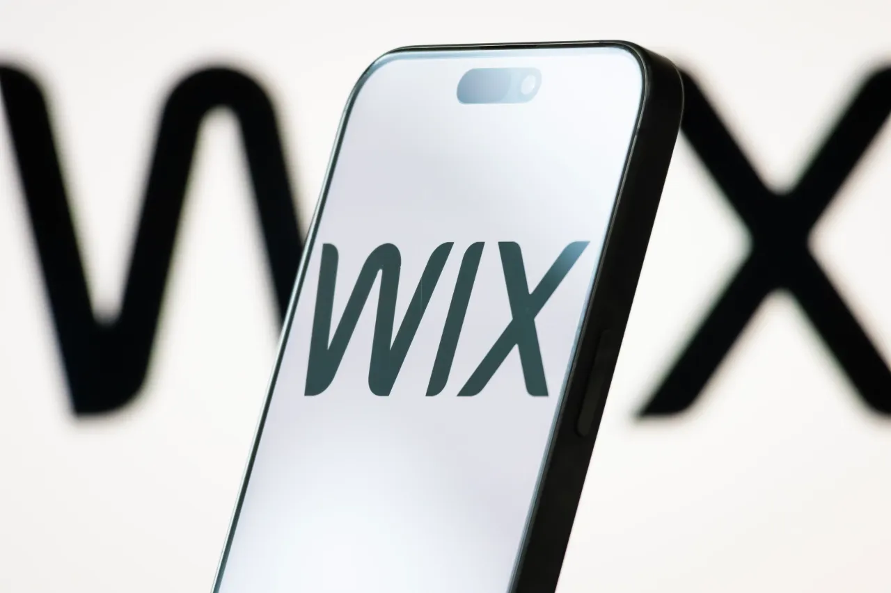 In this photo illustration, the logo of Wix.com Ltd. is displayed on a smartphone screen, with the company's minimalist black-and-white branding visible in the background. (Photo illustration by Cheng Xin/Getty Images)