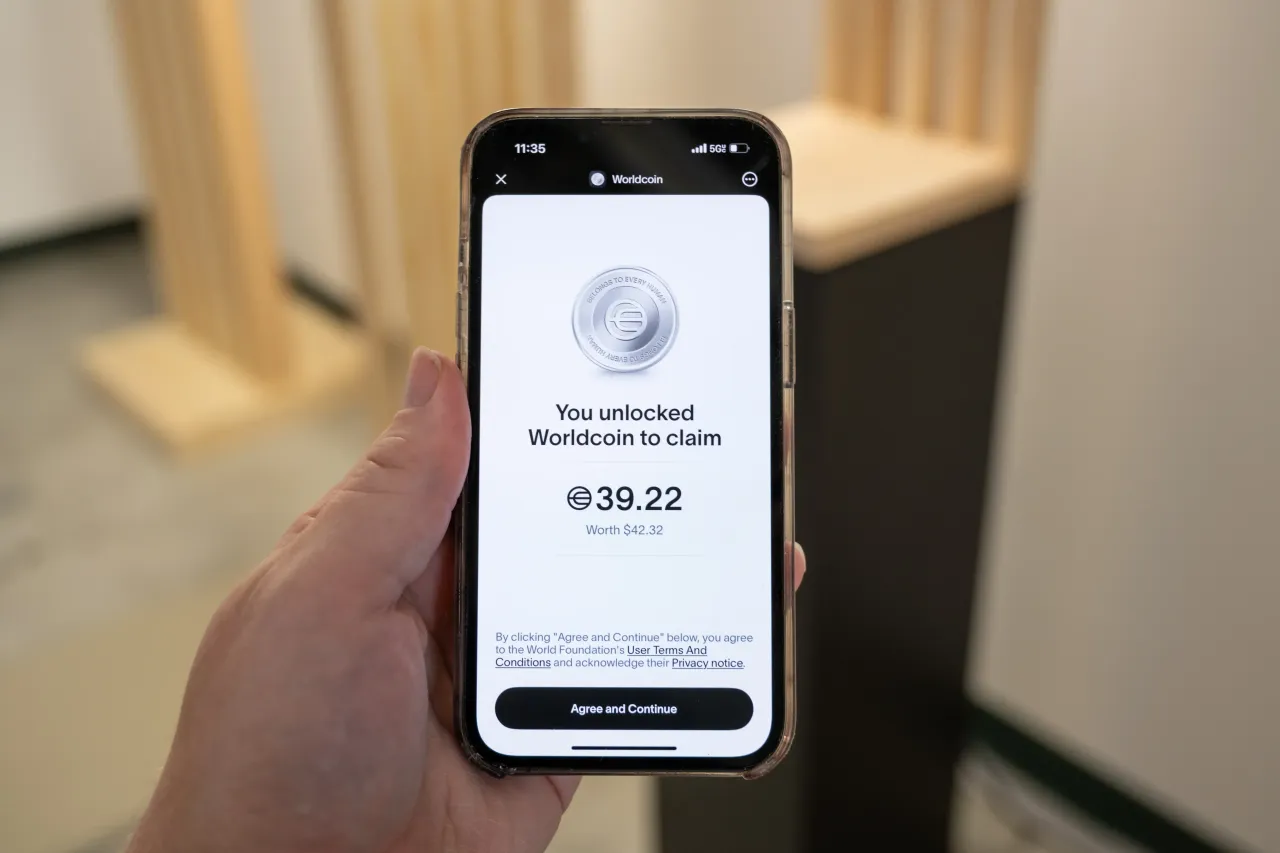 Hand holding smartphone running World app displaying unlocked Worldcoin balance of 39.22, Union Square, San Francisco, California, May 20, 2025. (Photo by Smith Collection/Gado/Getty Images)
