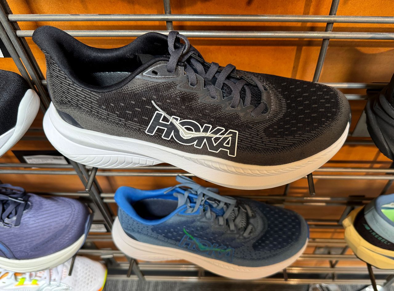 Hoka shoes are displayed on a shelf at an REI store.