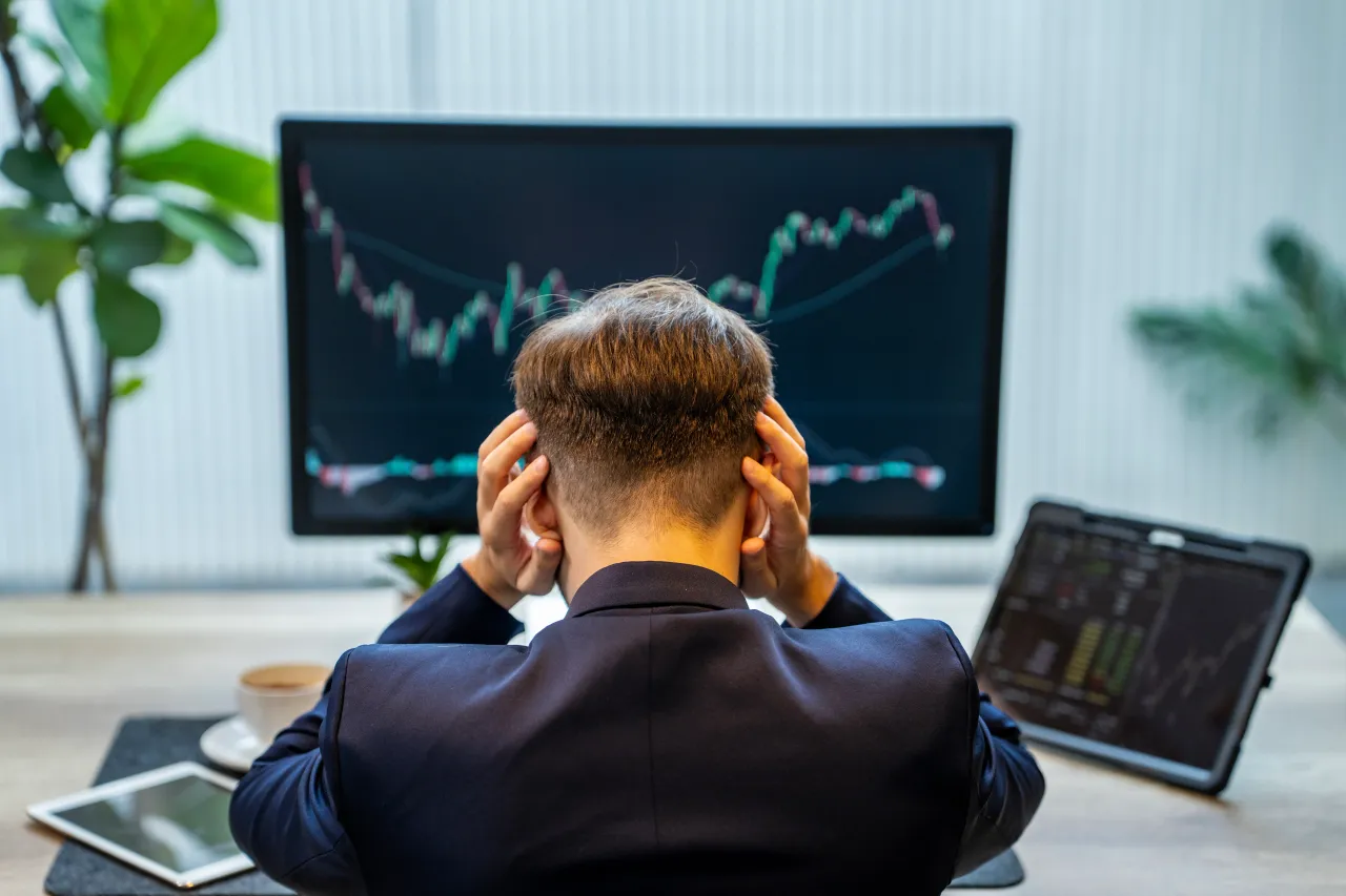 A young businessman covering his ears with his hands, sitting at his desk in front of computer showing declining stock market chart. Hedge fund manager Eric Jackson on Tuesday announced his new venture. (Source: Getty Images)