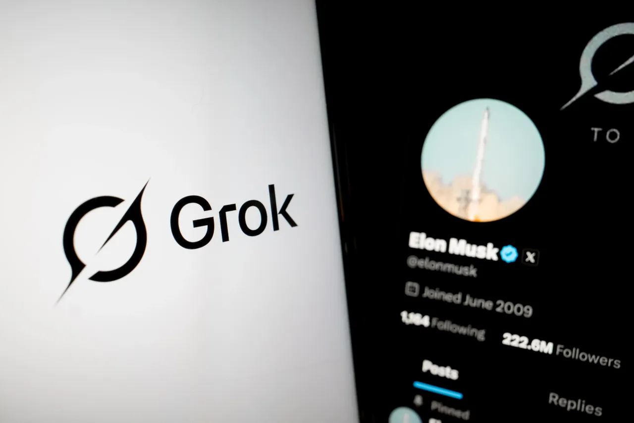The Grok logo on a smartphone screen, and the X (formerly Twitter) of Elon Musk appears as the background on a laptop screen. (Photo by Nikolas Kokovlis/NurPhoto via Getty Images)