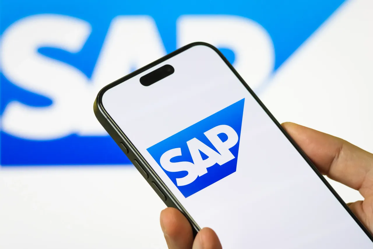 In this photo illustration, a person holds a smartphone displaying the logo of SAP SE (NYSE: SAP).