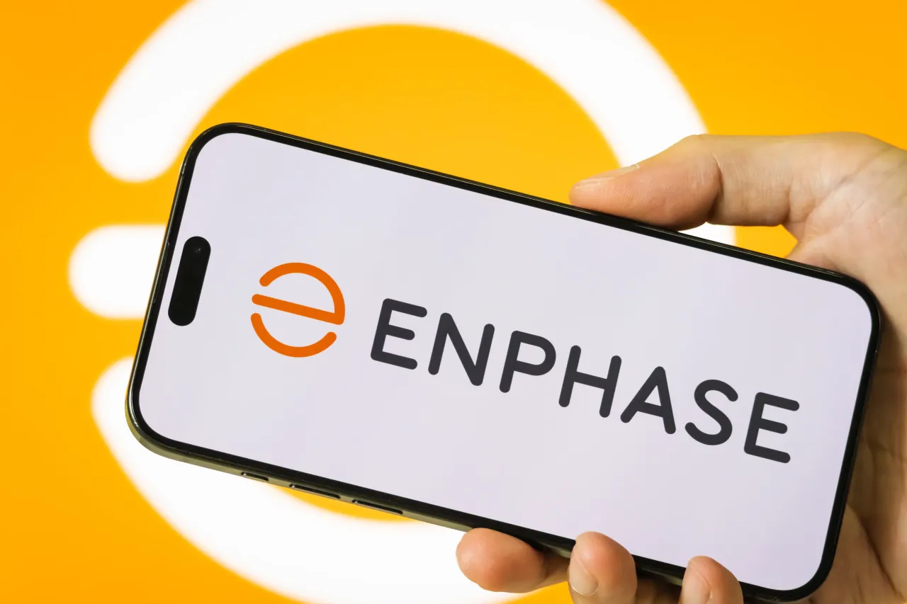 In this photo illustration, a person holds a smartphone displaying the logo of Enphase Energy Inc.