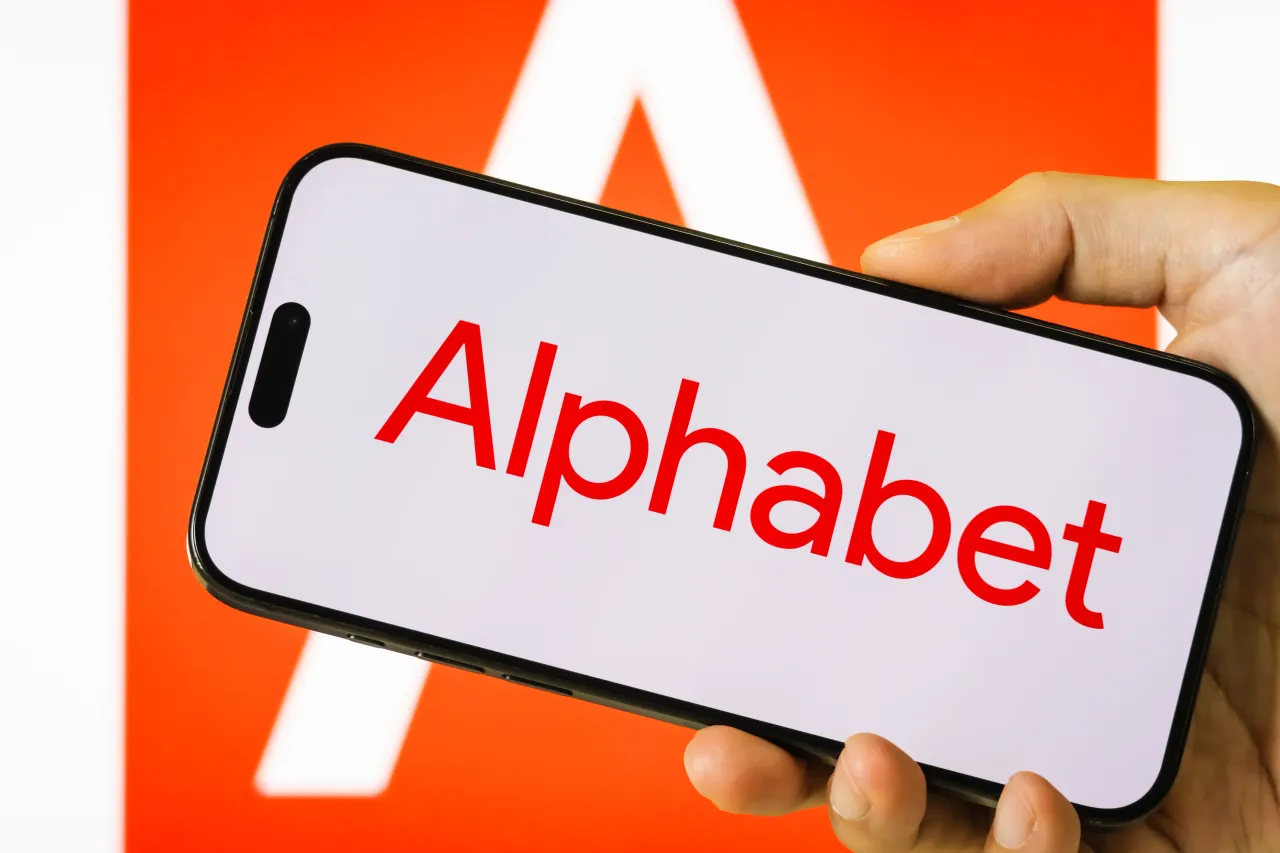 In this photo illustration, a person holds a smartphone displaying the logo of Alphabet Inc.