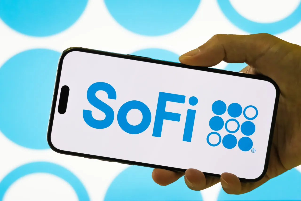 In this photo illustration, a person holds a smartphone displaying the logo of SoFi Technologies Inc.