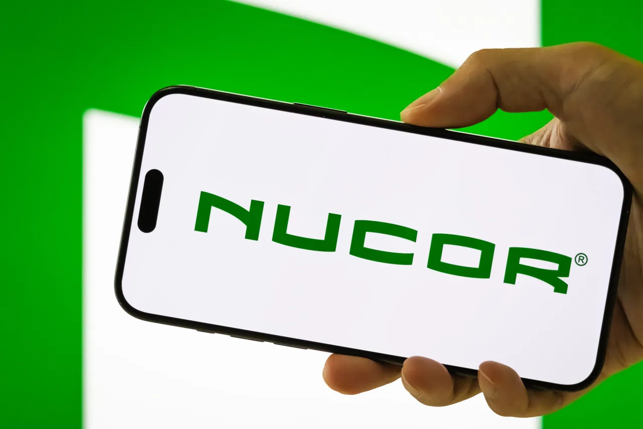 In this photo illustration, a person holds a smartphone displaying the logo of Nucor.