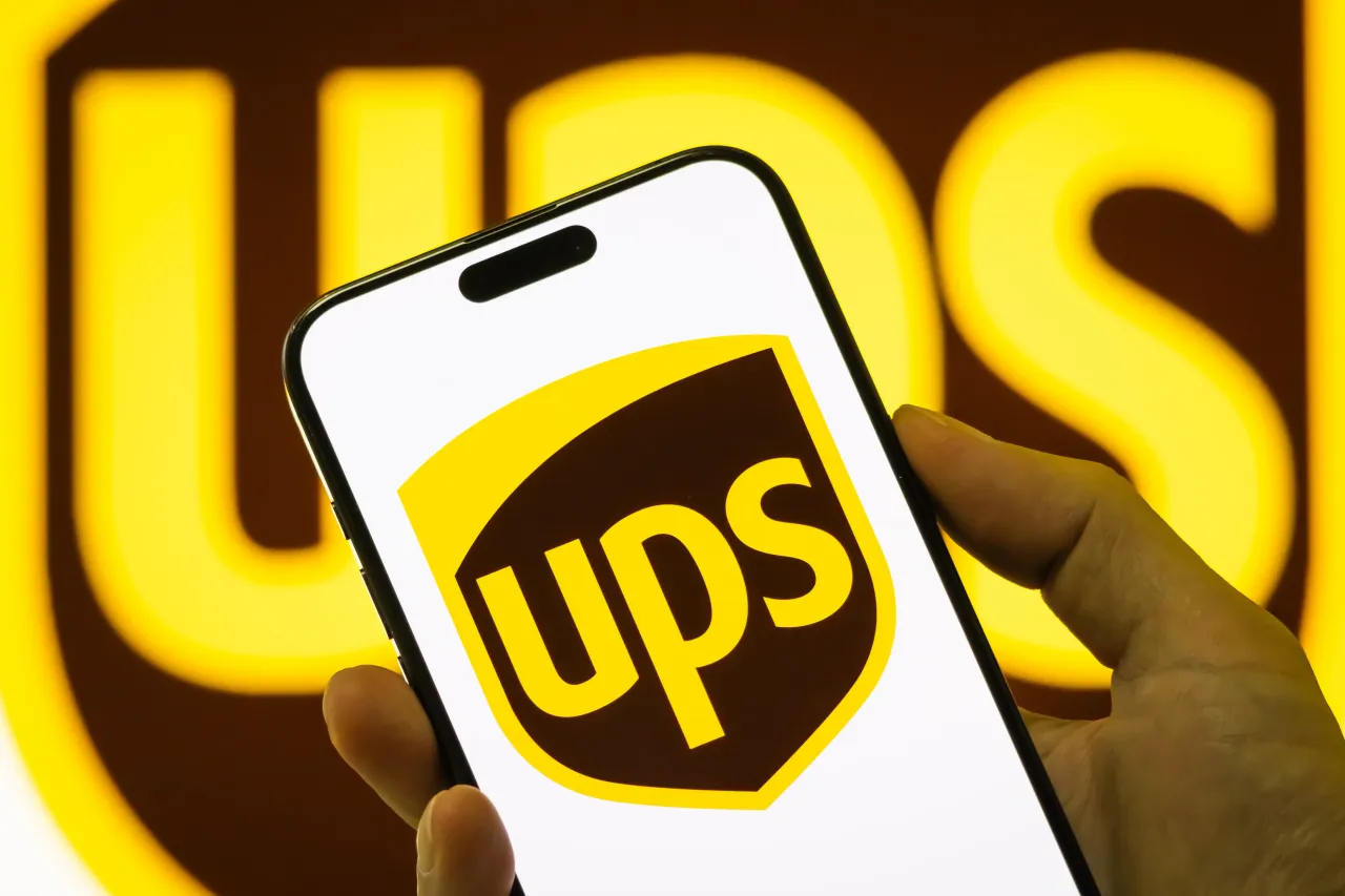  In this photo illustration, a person holds a smartphone displaying the logo of United Parcel Service Inc.