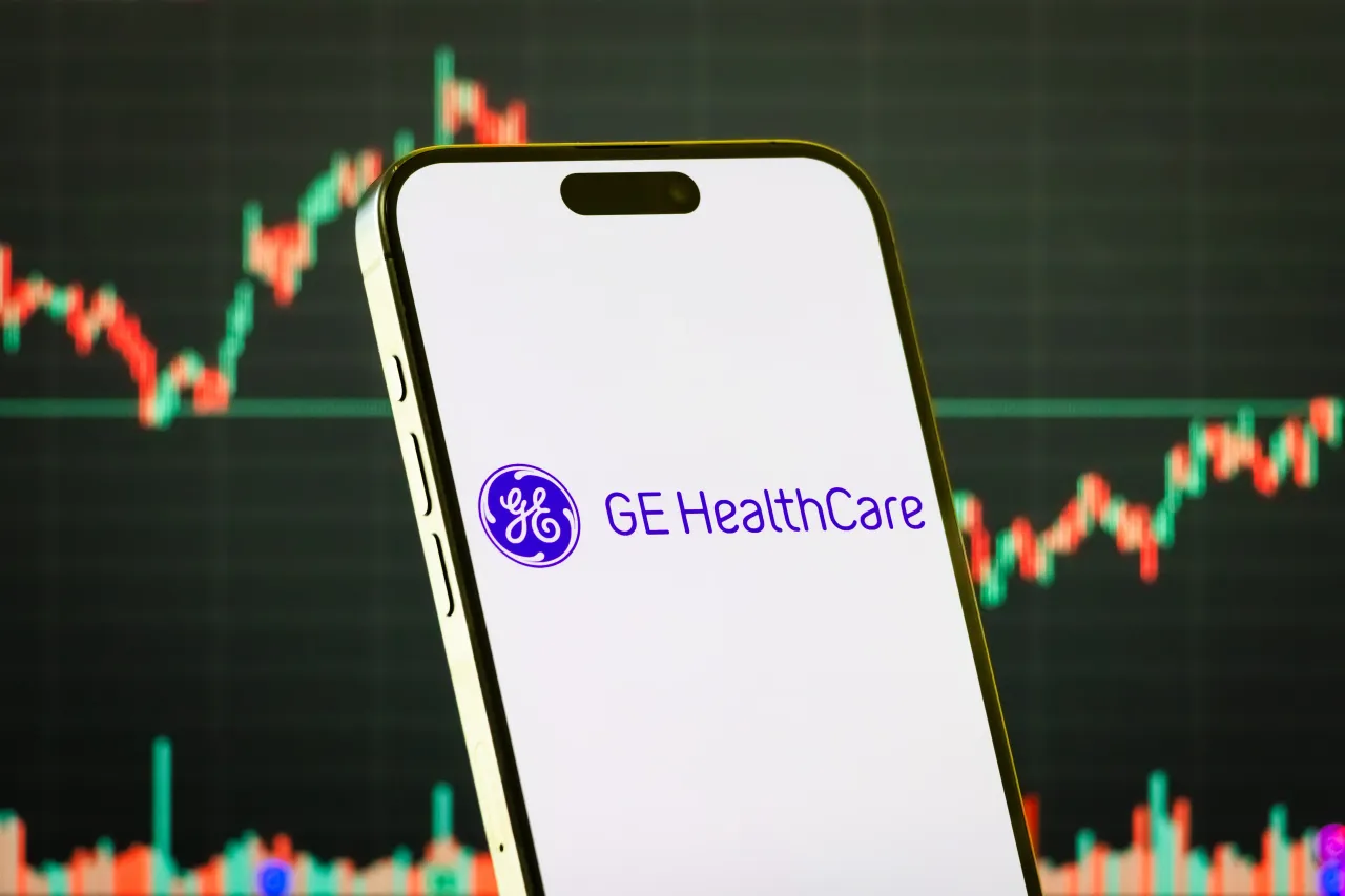 In this photo illustration, a smartphone displays the logo of GE HealthCare Technologies Inc. in front of a screen showing the company's latest stock market chart on July 28, 2025 in Chongqing, China. (Photo illustration by Cheng Xin/Getty Images)