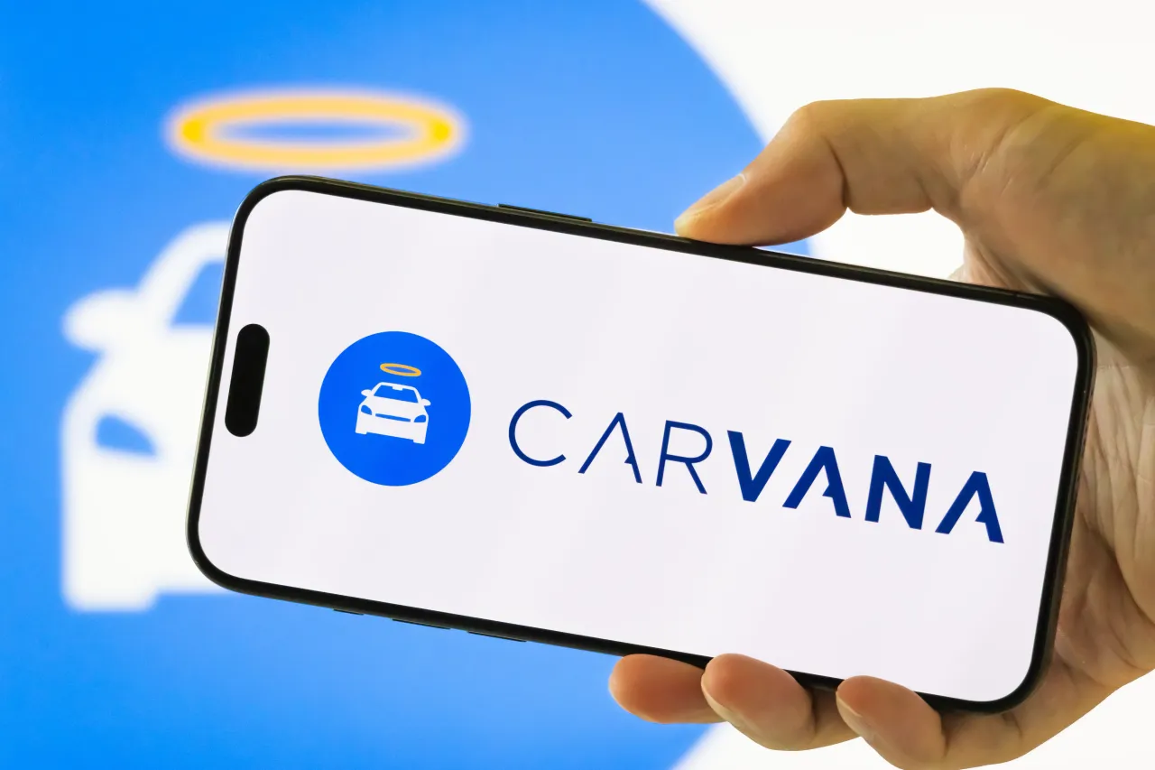 In this photo illustration, a person holds a smartphone displaying the logo of Carvana. (Photo illustration by Cheng Xin/Getty Images)