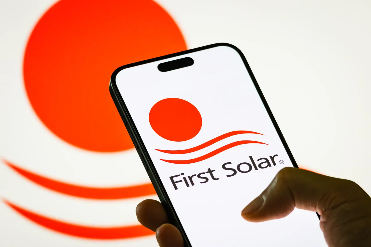 In this photo illustration, a person holds a smartphone displaying the logo of First Solar Inc.