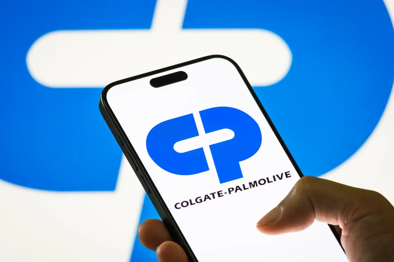 A person holds a smartphone displaying the logo of Colgate-Palmolive Co.