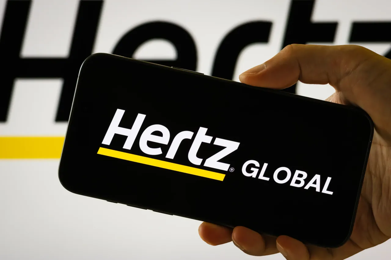  In this photo illustration, a person holds a smartphone displaying the logo of Hertz Global Holdings Inc. 