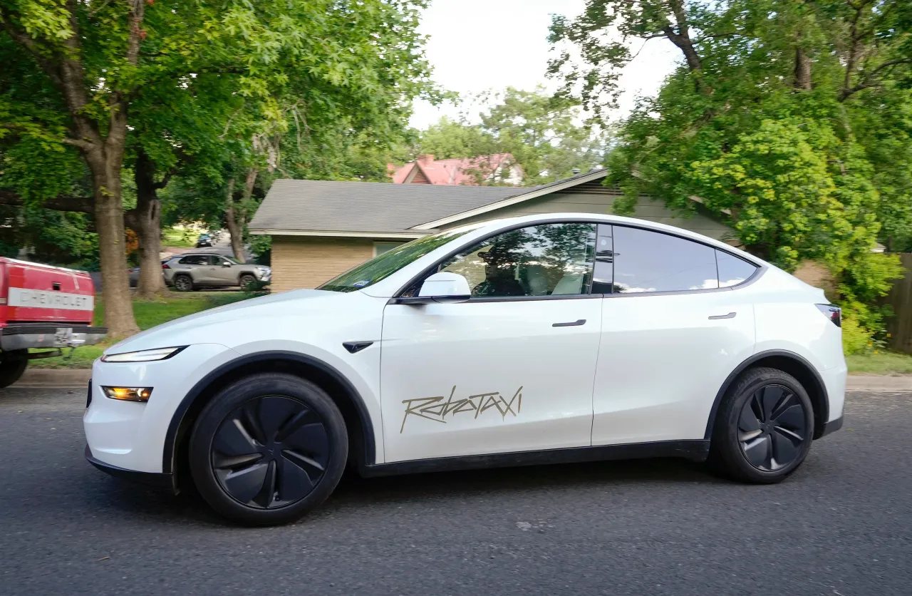 A driverless Tesla Robotaxi, with a man serving as a safety monitor in the front passenger seat, rolls along Laguna Drive in Southeast Austin, Friday, June 27, 2025. (Jay Janner/Austin American-Statesman via Getty Images)