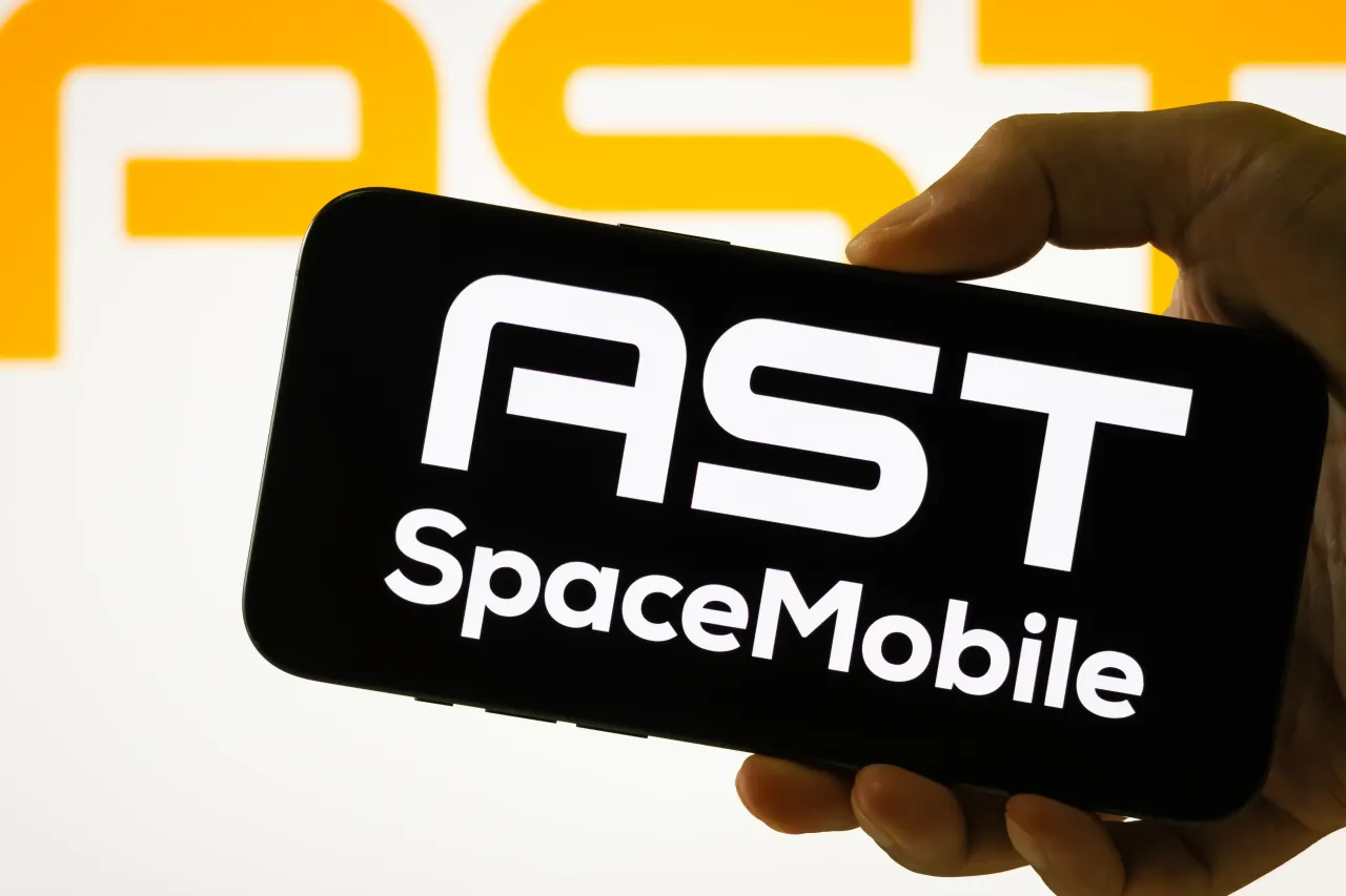  In this photo illustration, a person holds a smartphone displaying the logo of AST SpaceMobile.