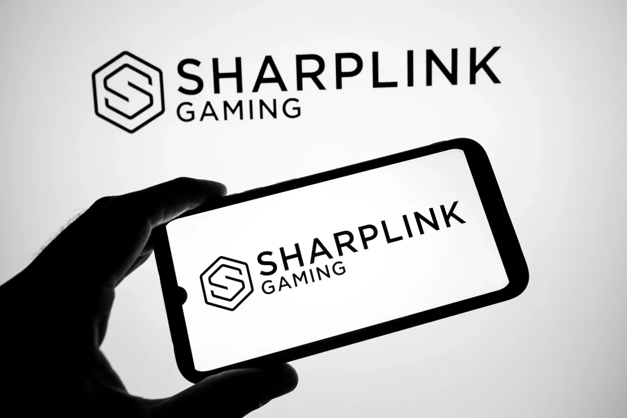 The SharpLink Gaming appears on a smartphone screen and as a background on a laptop computer screen in this photo illustration in Athens, Greece, on August 14, 2025. (Photo by Nikolas Kokovlis/NurPhoto via Getty Images)