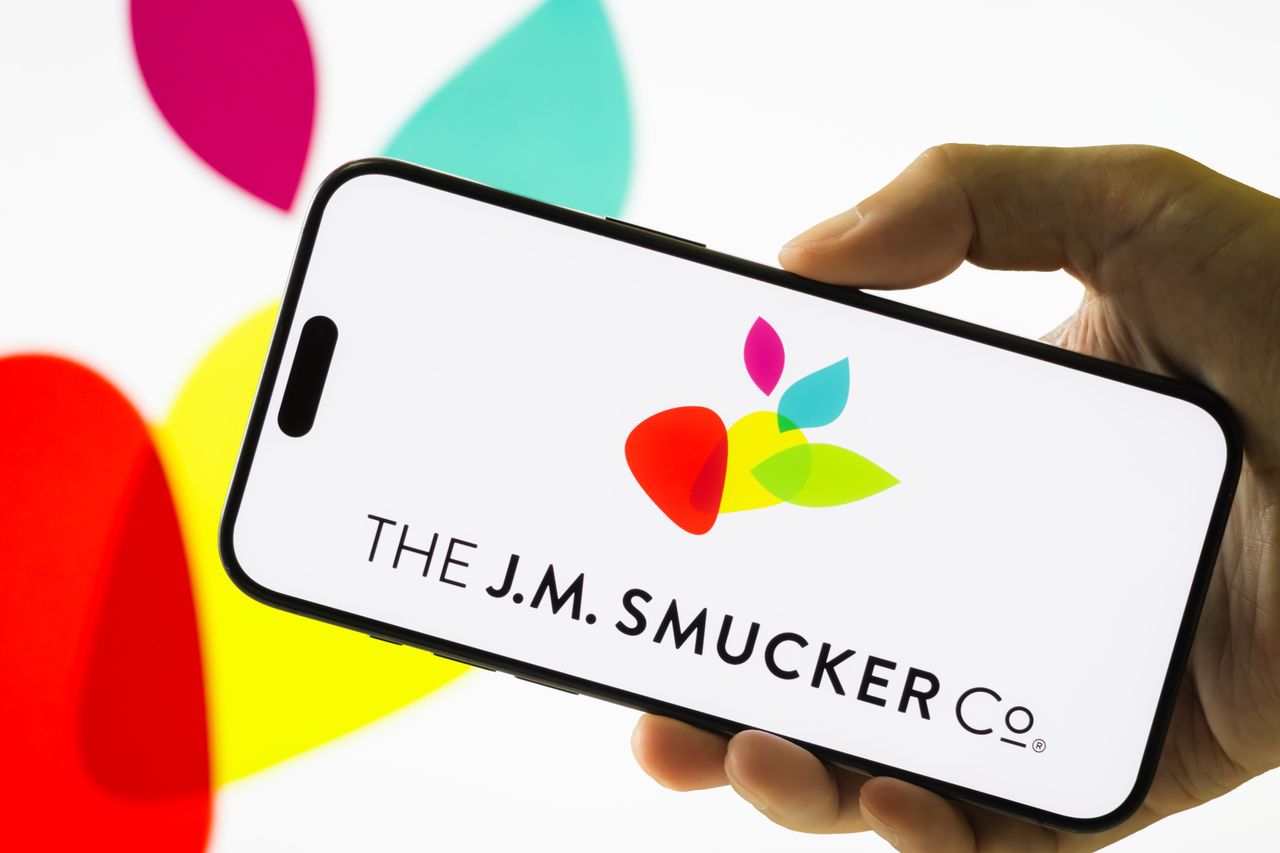 In this photo illustration, a hand holds a smartphone displaying the logo of The J.M. Smucker Company.