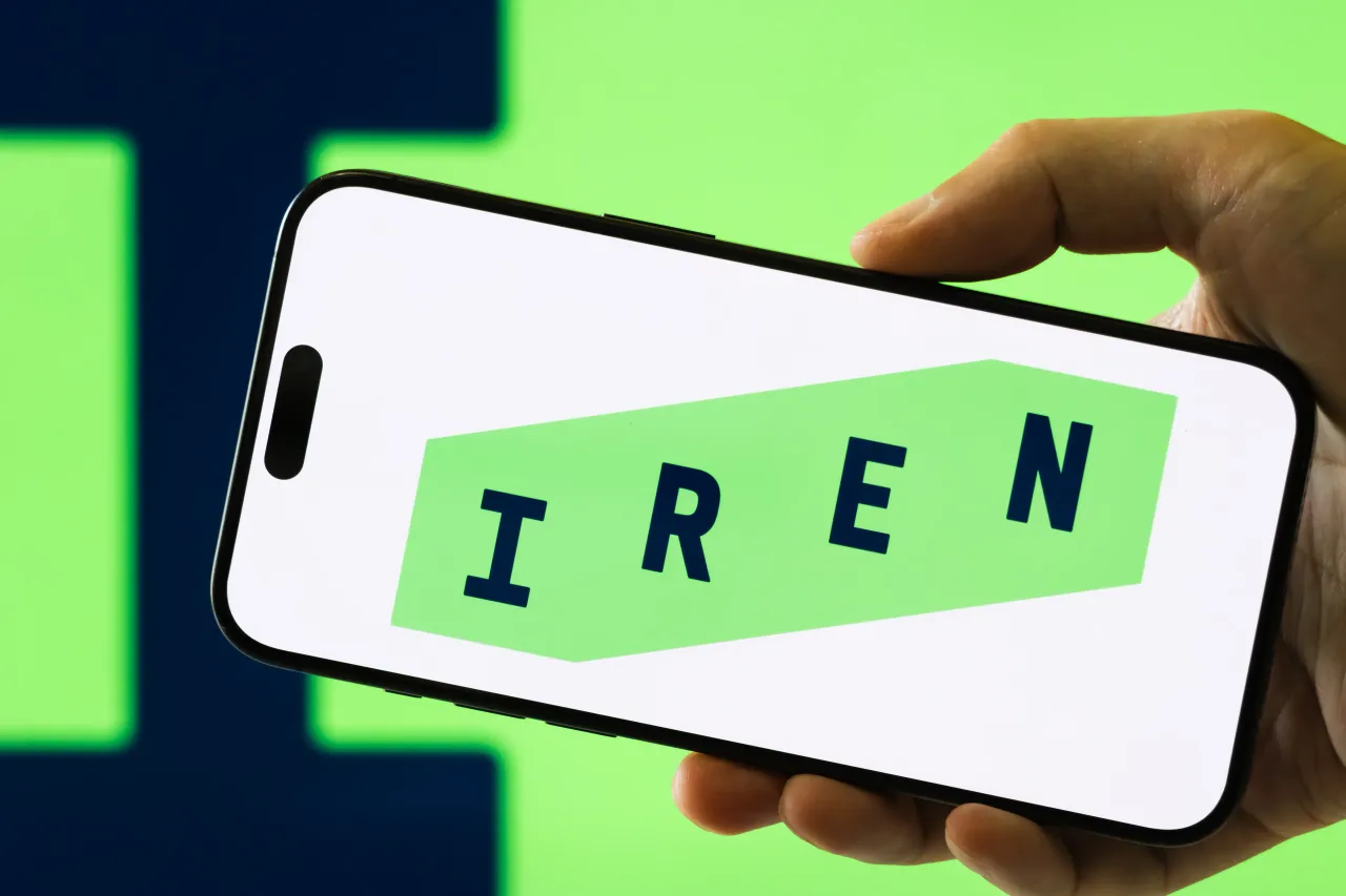 In this photo illustration, a person holds a smartphone displaying the logo of Iris Energy Limited. 