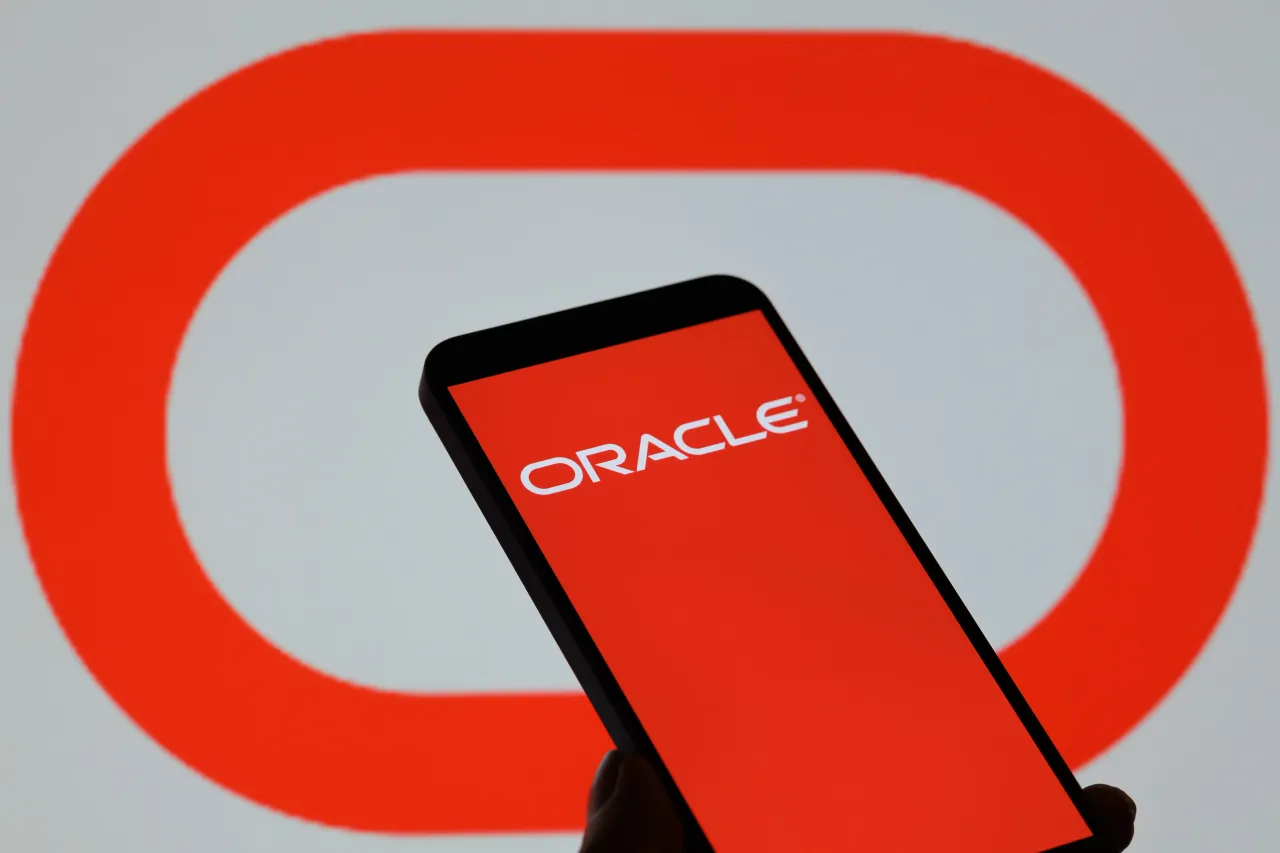 The Oracle logo is displayed on a mobile phone with the company's branding seen in the background. (Photo by Jonathan Raa/NurPhoto via Getty Images)