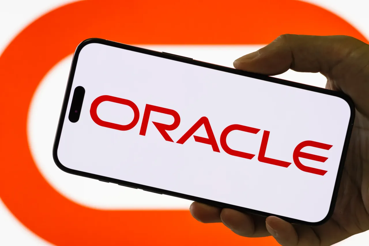 A smartphone held in a hand shows the logo of Oracle Corp. (Photo illustration by Cheng Xin/Getty Images)