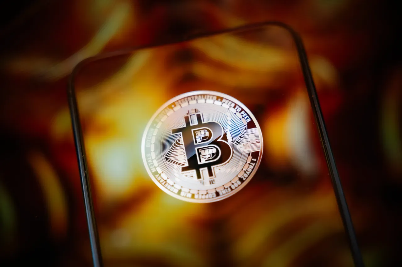 This photo shows a smartphone screen displaying the logo of a Bitcoin cryptocurrency token.