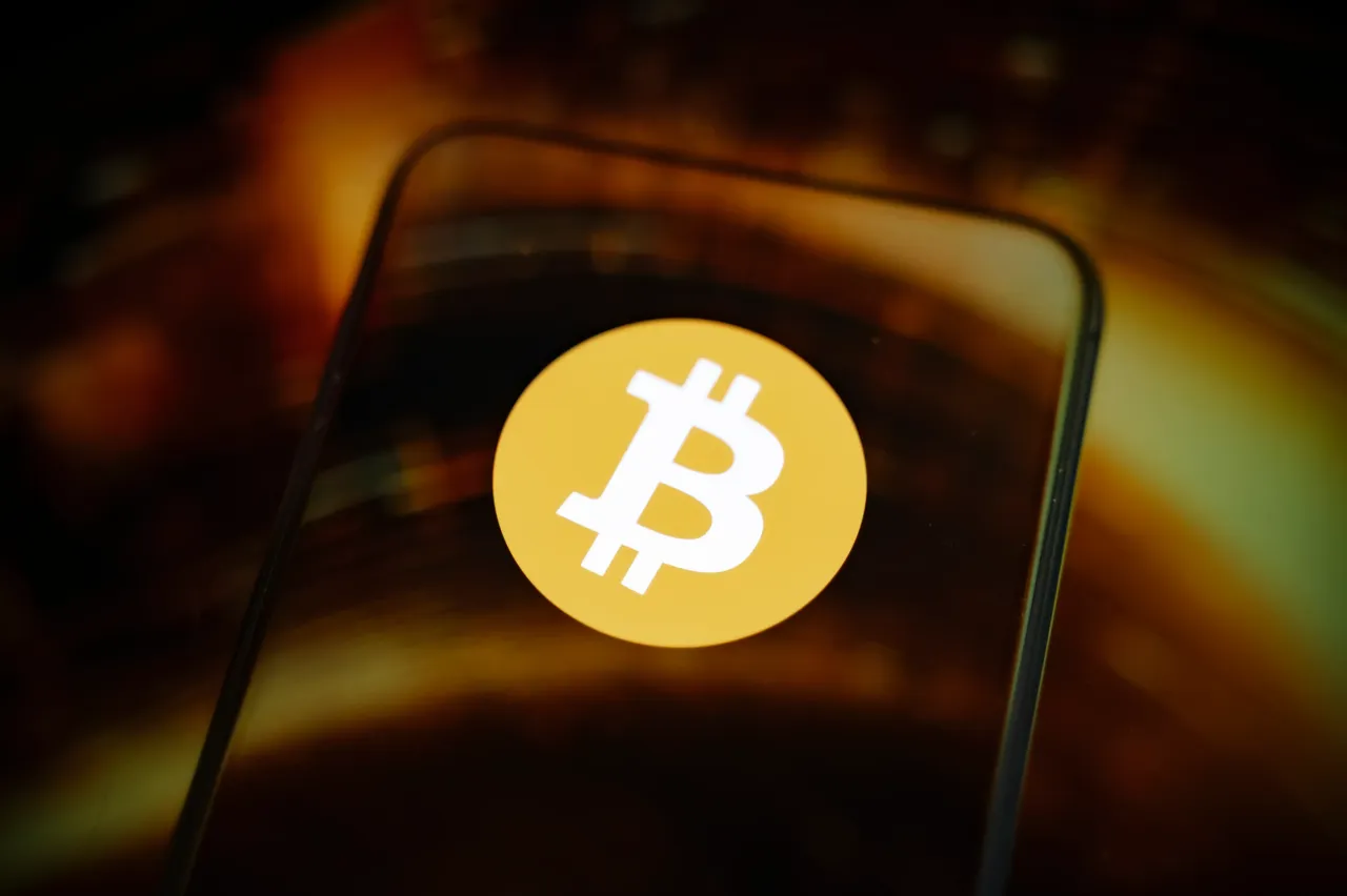 This photo shows a smartphone screen displaying the Bitcoin cryptocurrency logo.
