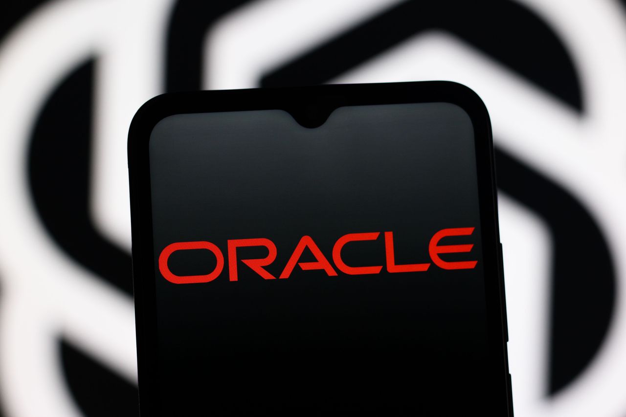 In this photo illustration, the Oracle Corporation logo is seen displayed on a smartphone screen and the OpenAI logo in the background. (Photo Illustration by Thomas Fuller/SOPA Images/LightRocket via Getty Images)