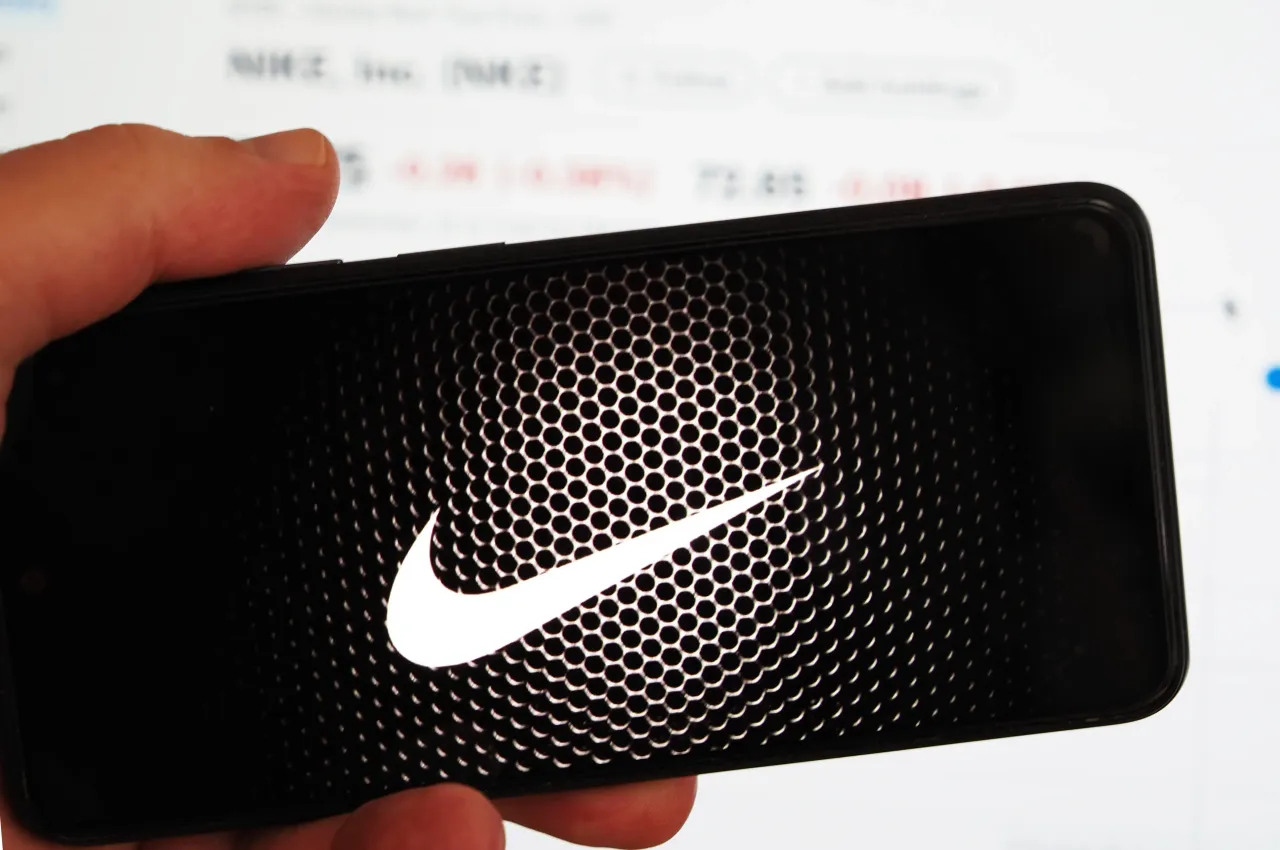 The Nike logo is displayed on a smartphone screen with a computer screen in the background. (Photo Illustration by Igor Golovniov/SOPA Images/LightRocket via Getty Images)