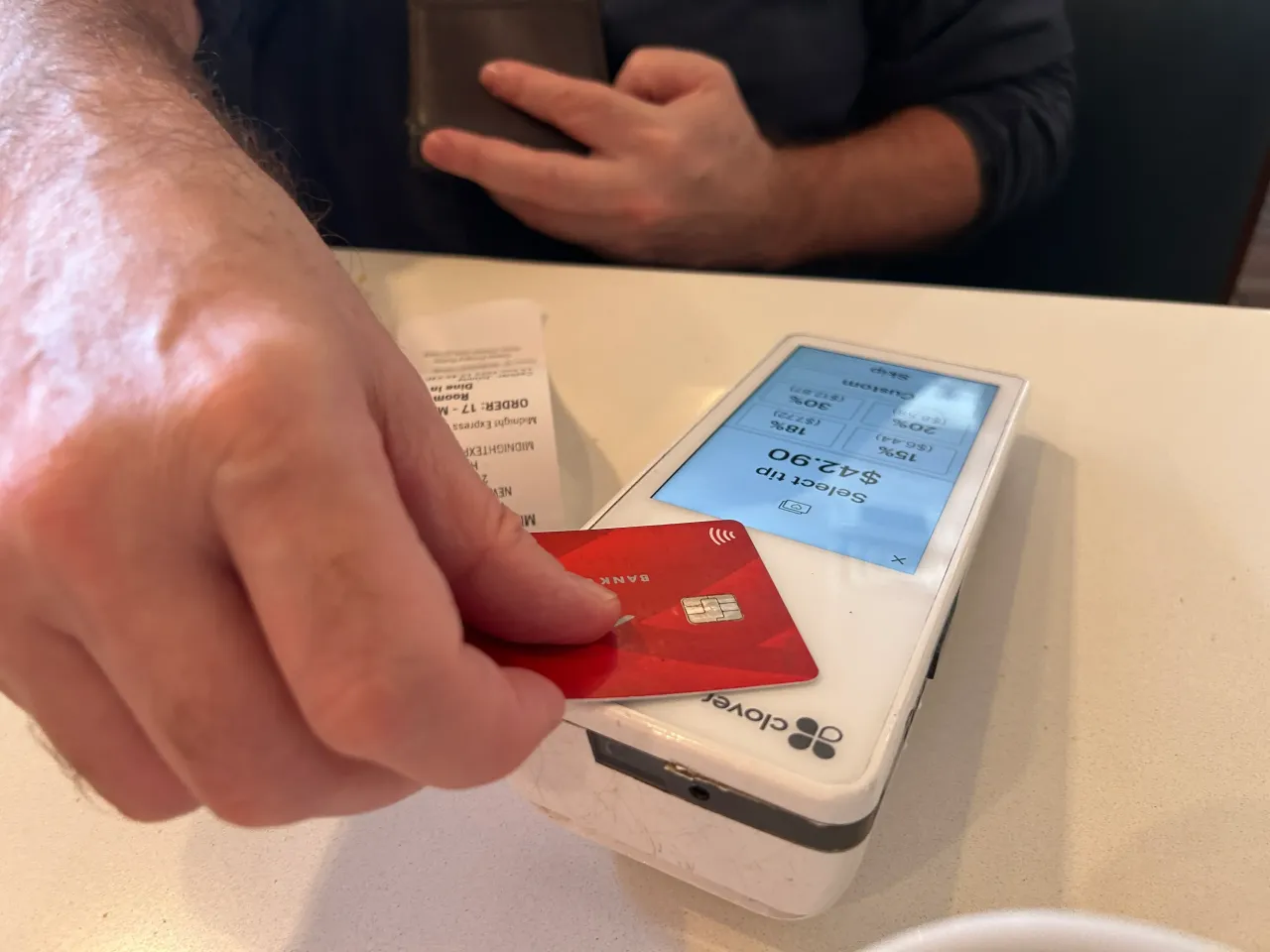 Man paying at a restaurant using a credit card and POS machine in Manhattan, New York City. (Photo by: Lindsey Nicholson/UCG/Universal Images Group via Getty Images)
