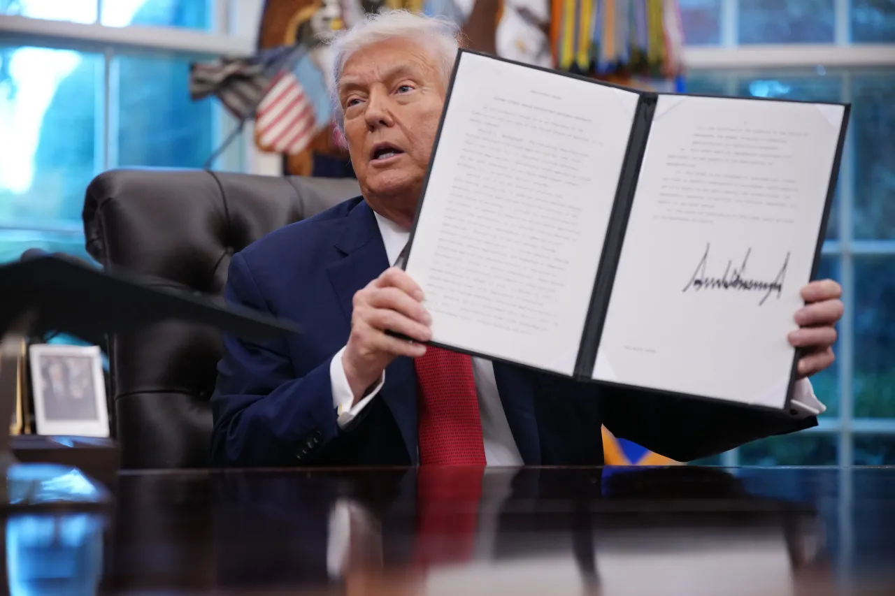 Donald Trump displays a signed executive order in the Oval Office of the White House on September 25, 2025 in Washington, DC. (Photo by Andrew Harnik/Getty Images)