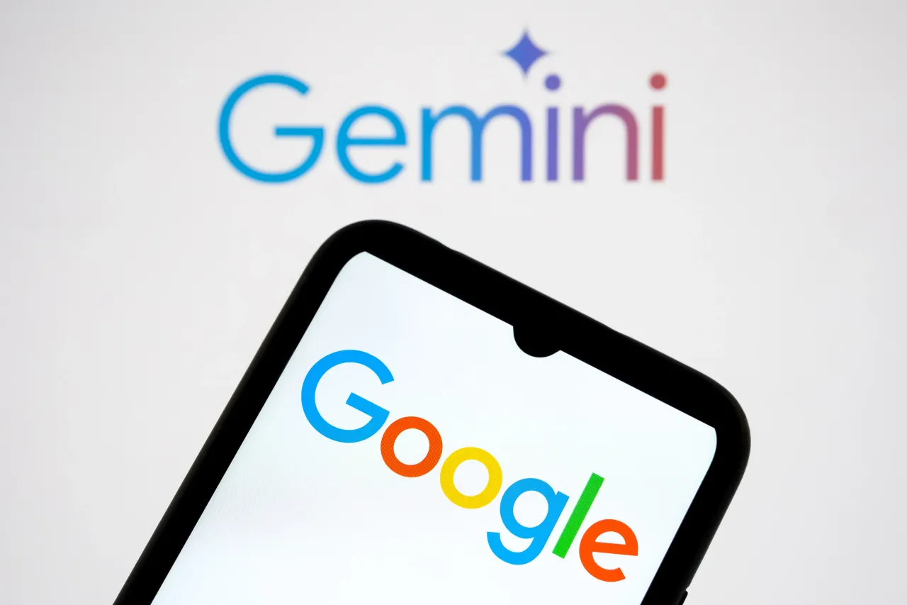 The Google logo appears on a smartphone screen, and the Gemini logo serves as the background. (Photo by Nikolas Kokovlis/NurPhoto via Getty Images)