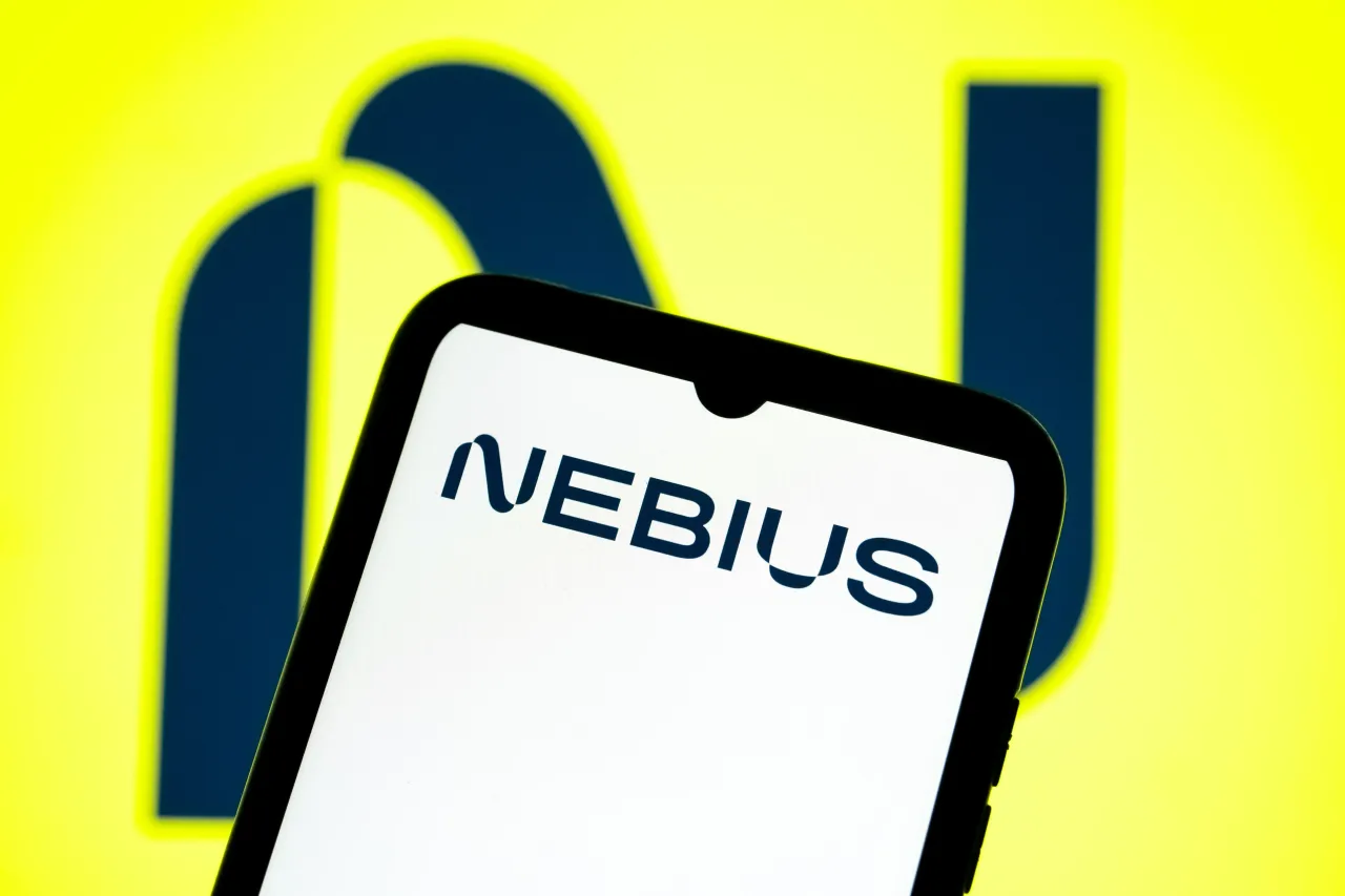 The Nebius AI logo appears on a smartphone screen and as the background on a laptop computer screen. (Photo Illustration by Nikolas Kokovlis/NurPhoto via Getty Images)