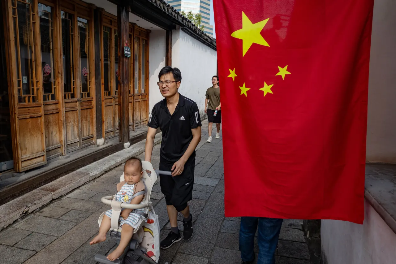 A man pushes a stroller with a baby near a Chinese national flag at a scenic spot. (Photo by Sheldon Cooper/SOPA Images/LightRocket via Getty Images)