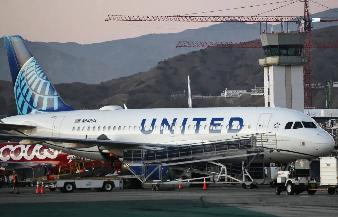 The Hollywood Burbank Airport air traffic control tower stands (R) beyond a parked United Airlines plane on October 6, 2025 in Burbank, California. 