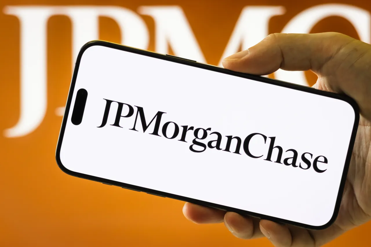 In this photo illustration, a smartphone held in a hand displays the logo of JPMorgan Chase & Co.