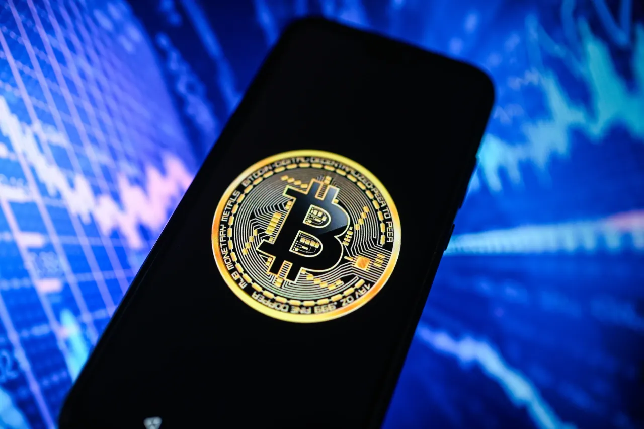 In this photo illustration, a Bitcoin logo is displayed on a smartphone with an illustration of graphs in the background. (Photo Illustration by Omar Marques/SOPA Images/LightRocket via Getty Images)