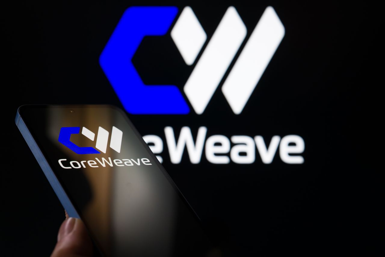The CoreWeave logo is displayed on a mobile phone, with the company's branding visible in the background. (Photo by Jonathan Raa/NurPhoto via Getty Images)
