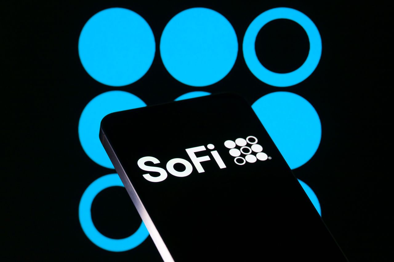 The SoFi Technologies Inc logo is displayed on a mobile phone with the company branding icon visible in the background. (Photo Illustration by Jonathan Raa/NurPhoto via Getty Images)