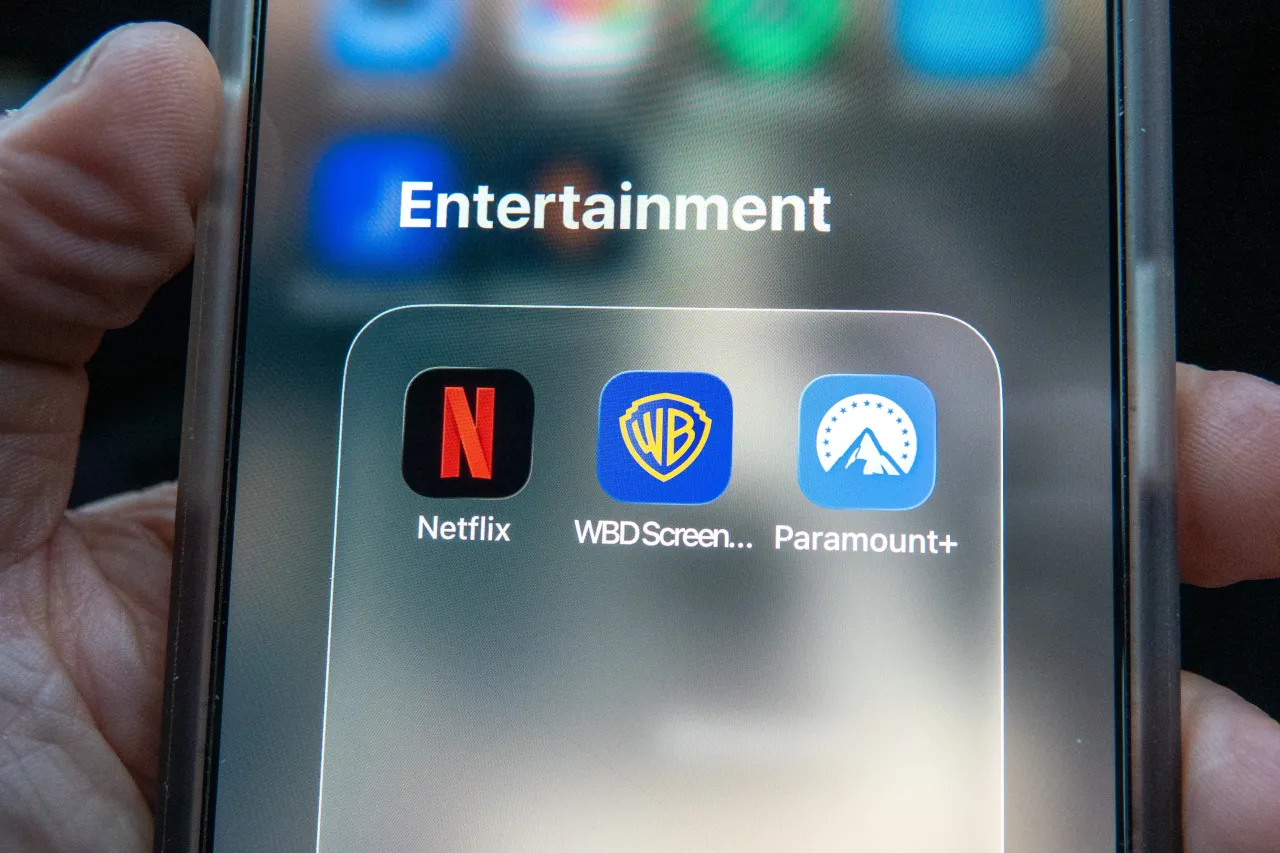 A phone screen shows Netflix, Warner Bros and Paramount streaming apps. (Photo by Anna Barclay/Getty Images)