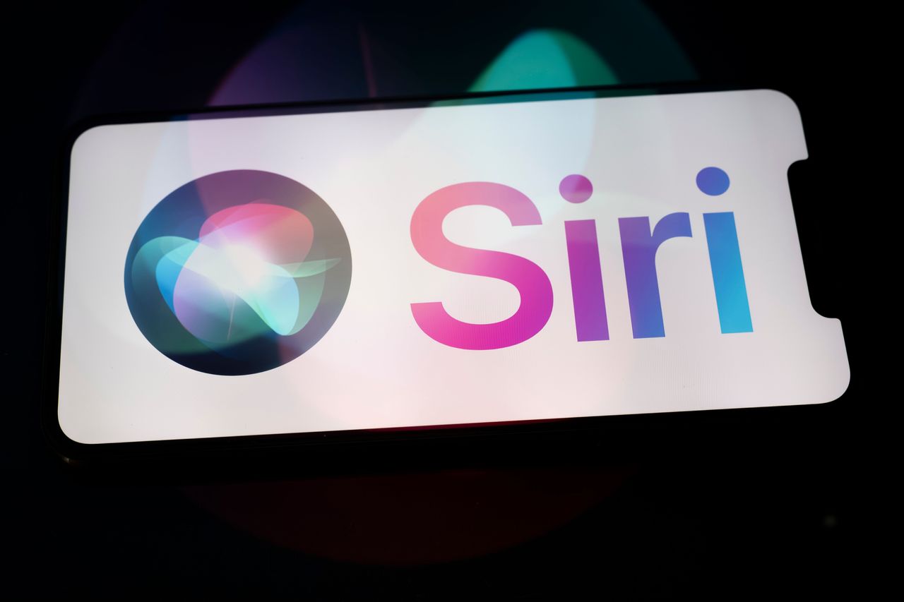 The Siri logo appears on the screen of a smartphone placed on a surface reflecting the new Siri logo. (Photo by Samuel Boivin/NurPhoto via Getty Images)